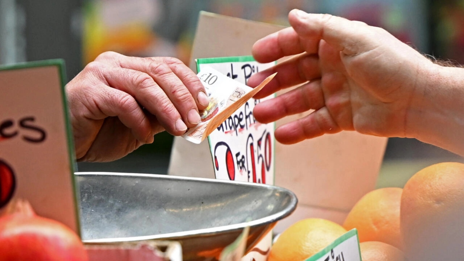 متسوق يدفع ثمن الفاكهة والخضار التي اشتراها بالجنيه الاسترليني، في متجر بلندن في 12 مايو 2022