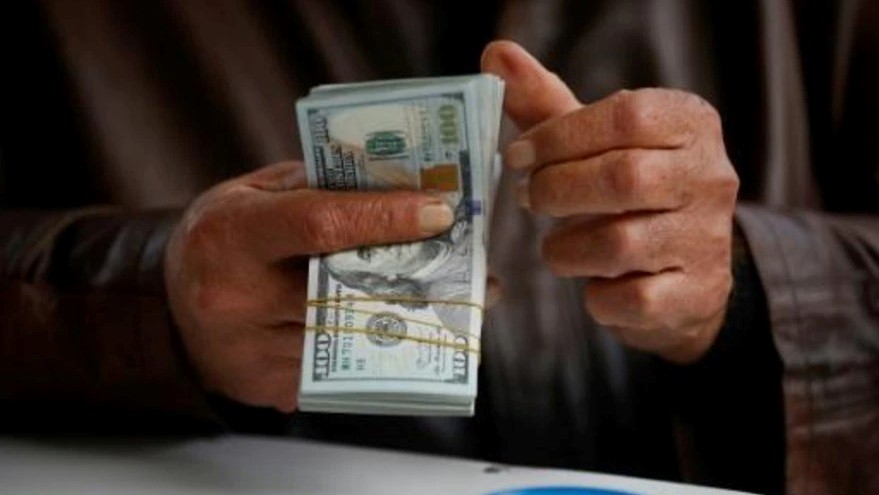 رجل يقوم بعدّ أوراق نقدية من الدولار في سوق مالي في بغداد بتاريخ 27 كانون الأول/ديسمبر 2022