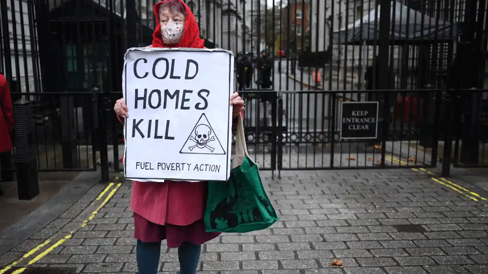 سيدة تقف خارج داونينج ستريت وتحمل لافتة تُسلِّط الضوء على معاناة البريطانيين في بيوتهم الباردة بسبب نقص الوقود 