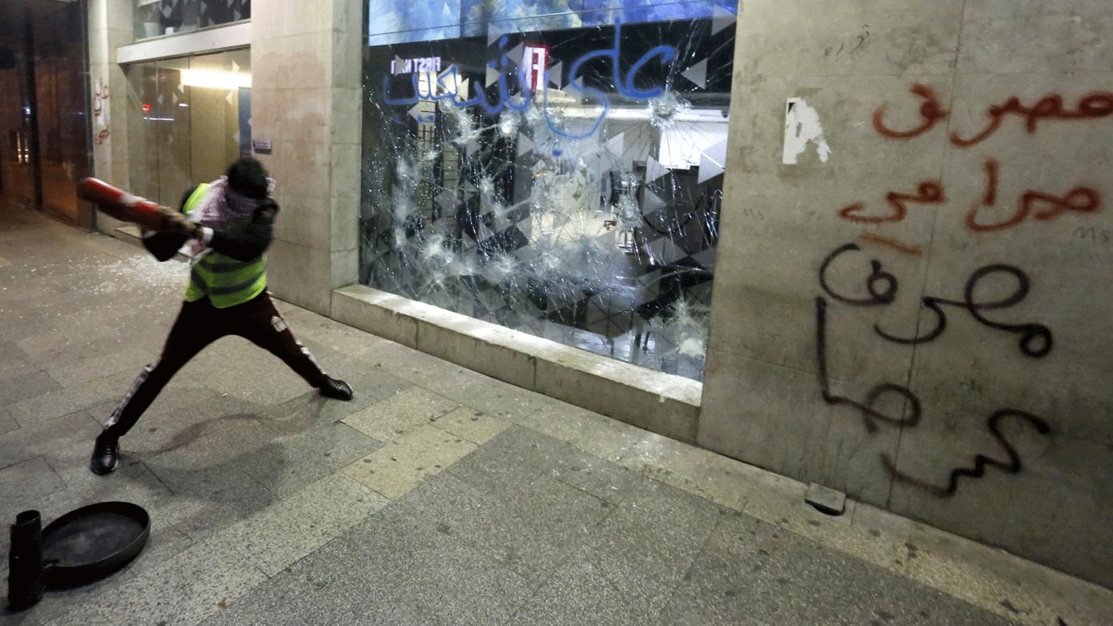متظاهر لبناني يحاول كسر نافذة بنك في العاصمة بيروت 