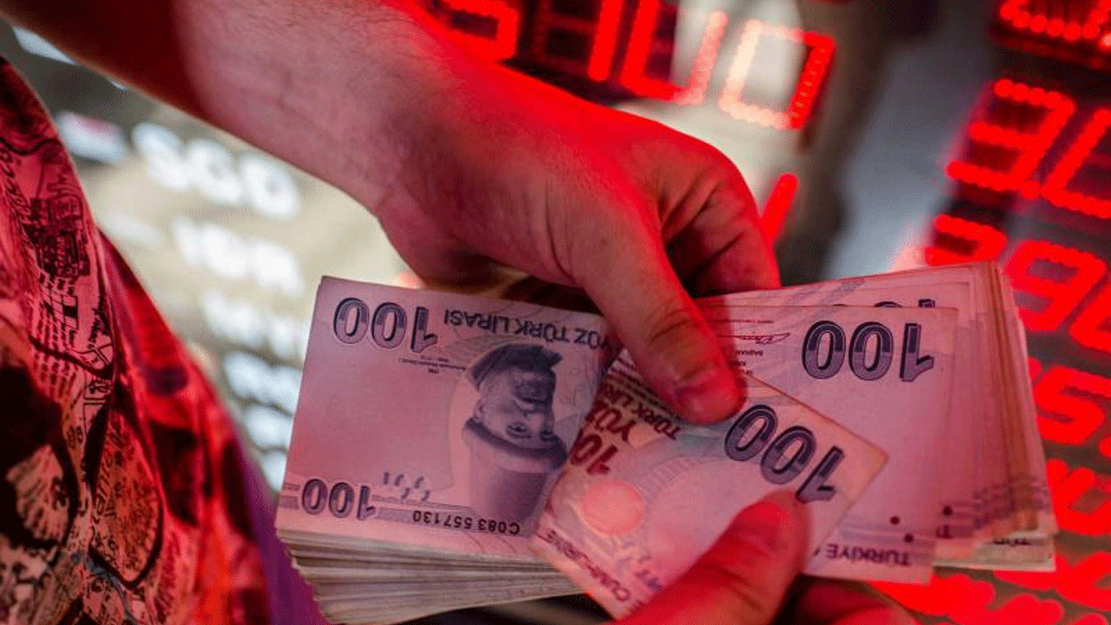 صرّاف يحصي الأوراق النقدية بالليرة التركية في مكتب صرف العملات في اسطنبول