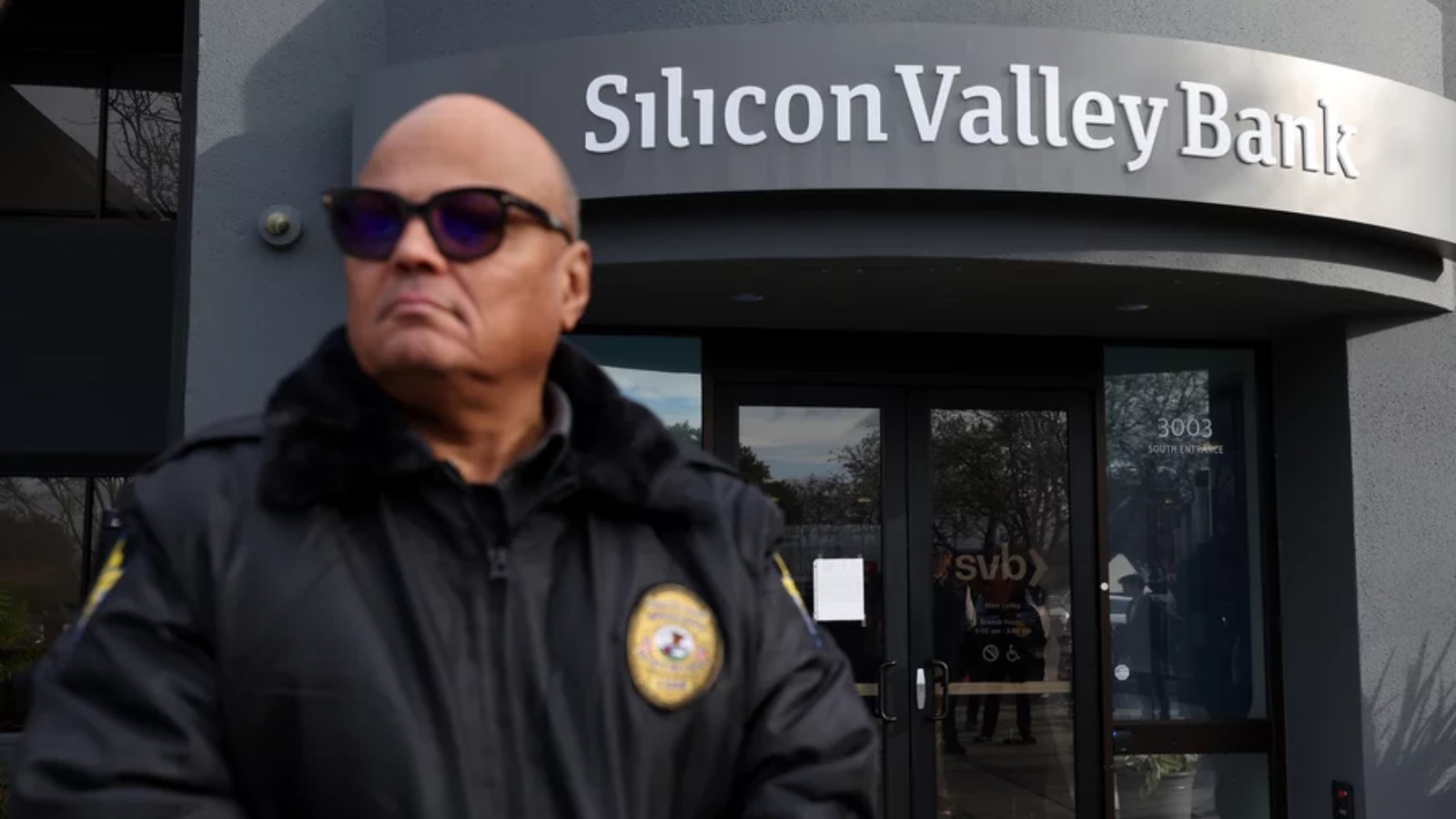 أحد حراس الأمن في سيليكون فالي بنك يراقب مجموعة من الأشخاص خارج المكتب في سانتا كلارا، كاليفورنيا، في 13 مارس 2023.