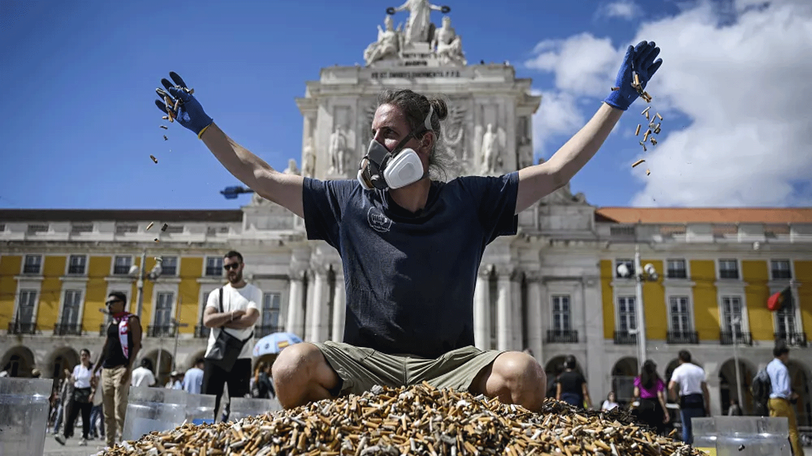 الناشط البيئي الألماني، أندرياس نوي يجلس فوق كومة من أعقاب السجائر التي تم جمعها في أسبوع واحد، في ميدان كوميرسيو \ لشبونة 