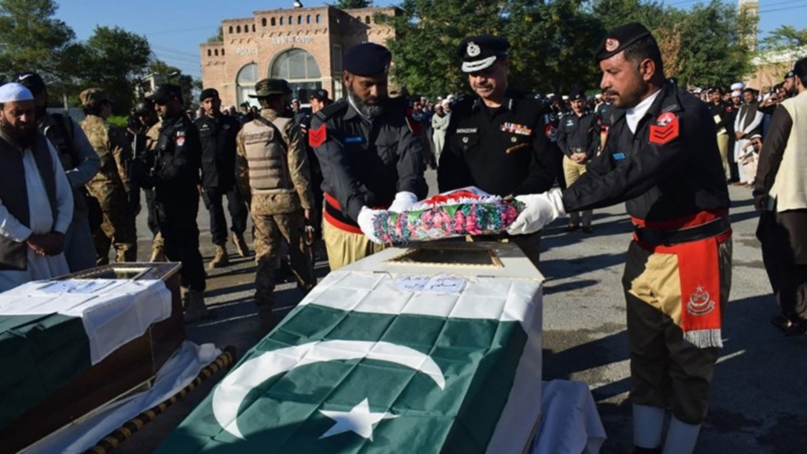 عناصر من الأمن يضعون إكليلاً من الزهور على نعش أحد العناصر الذين قتلوا في باكستان