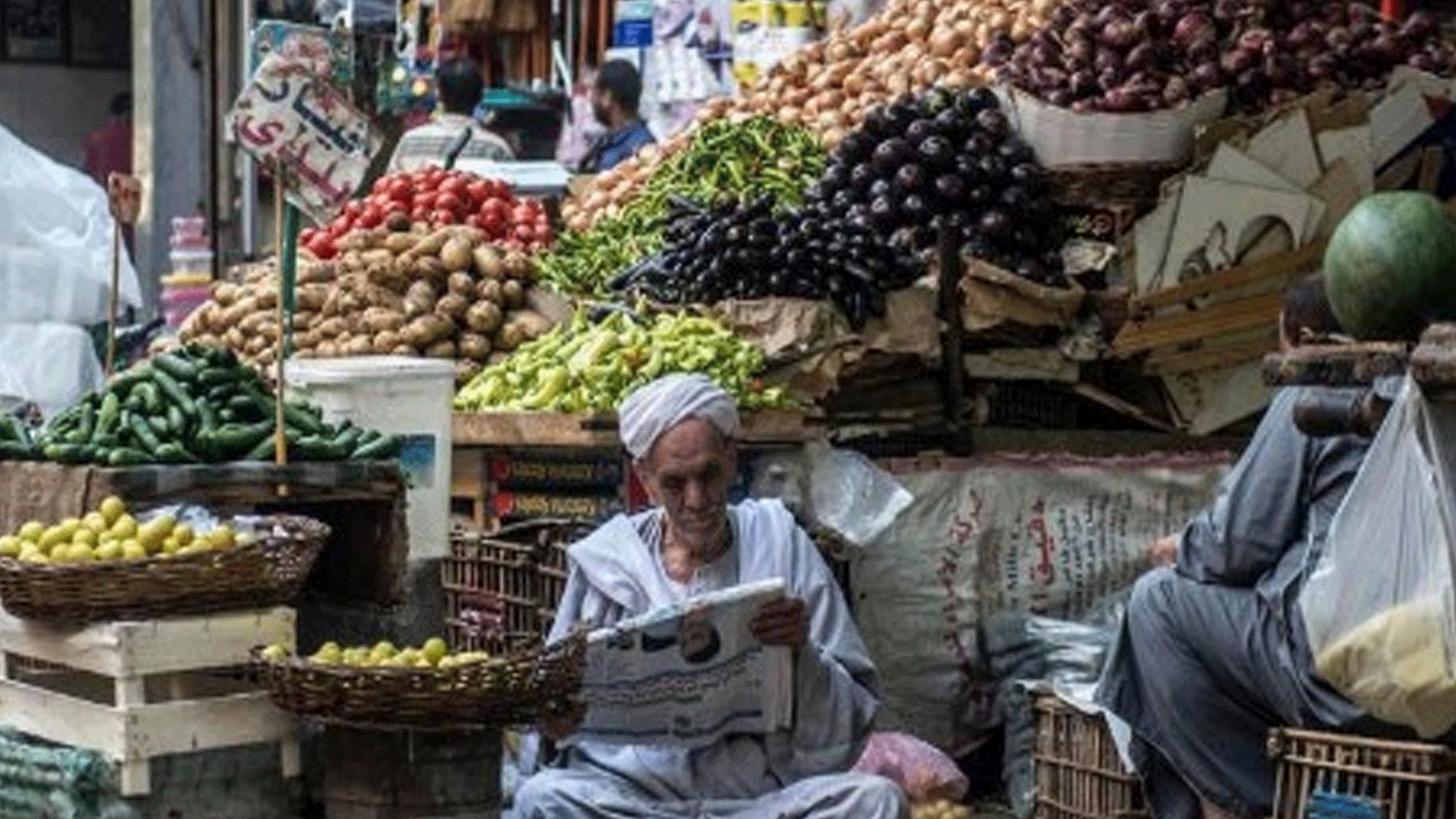 صورة أرشيفية لبائع خضراوات يقرأ جريدة بغياب الزبائن