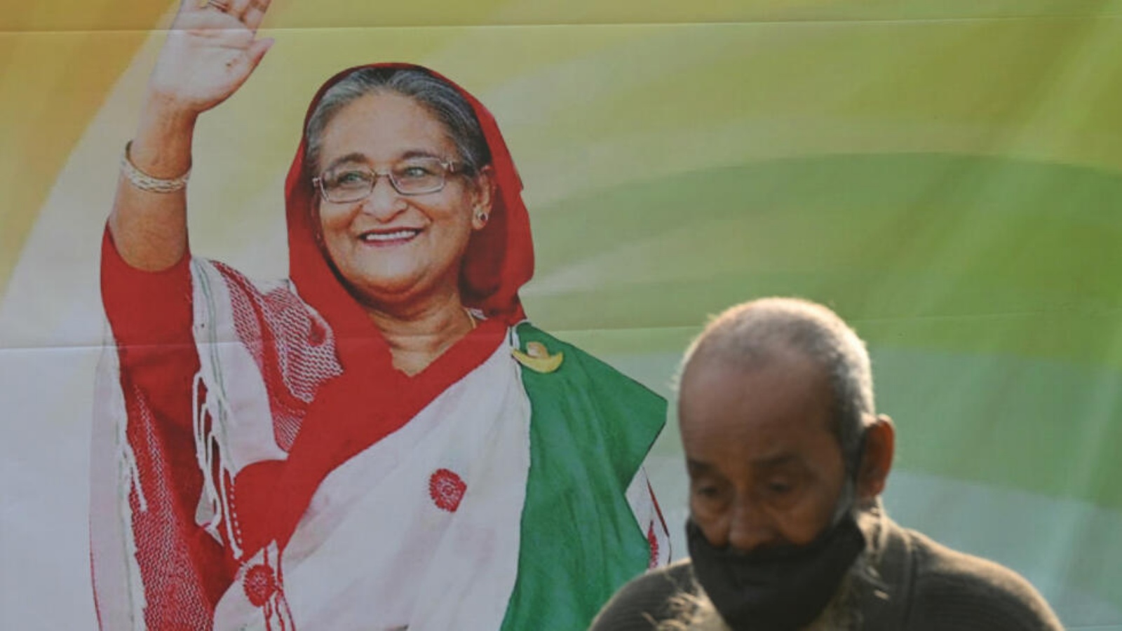 شخص يمرّ أمام صورة لرئيسة وزراء بنغلادش الشيخة حسينة في دكا بتاريخ الخامس من يناير 2024 