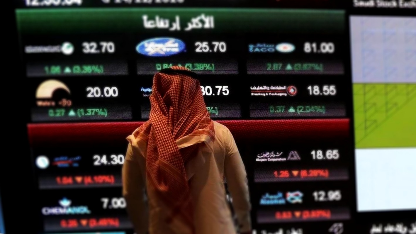 أحد المتداولين يتابع الأسواق من خلال شاشة عملاقة في سوق الأسهم السعودي