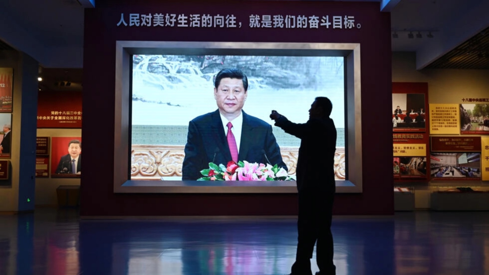 رجل امام فيديو لخطاب للرئيس الصيني شي جينبينغ في متحف الحزب الشيوعي الصيني في بكين في 29 شباط (فبراير) 2024