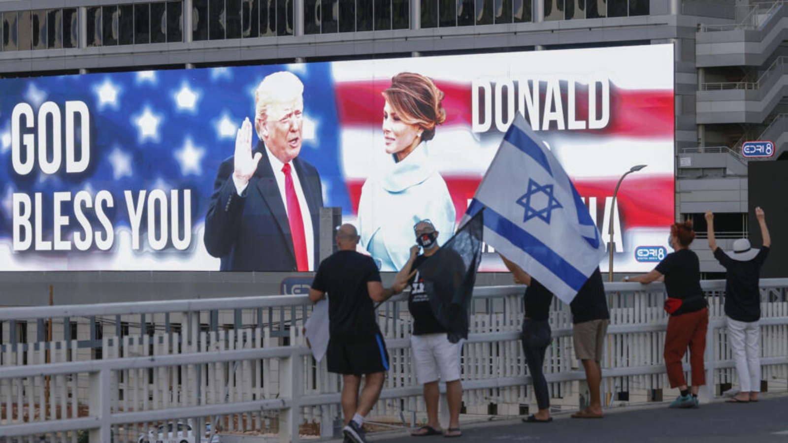 متظاهرون مناهضون للحكومة الإسرائيلية يرفعون العلم الإسرائيلي على جسر أمامه صورة كبيرة لدونالد ترامب وزوجته ميلانيا في تل أبيب بتاريخ 3 تشرين الأول/أكتوبر 2020 متظاهرون مناهضون للحكومة الإسرائيلية يرفعون العلم الإسرائيلي على جسر أمامه صورة كبيرة لدونالد ترامب وزوجته ميلانيا في تل أبيب بتاريخ 3 تشرين الأول (أكتوبر) 2020 