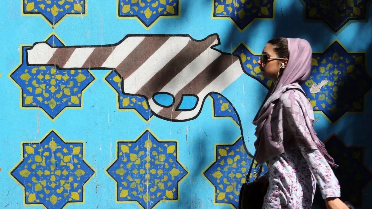 فتاة تمر أمام جدار المقر السابق للسفارة الأميركية في طهران
