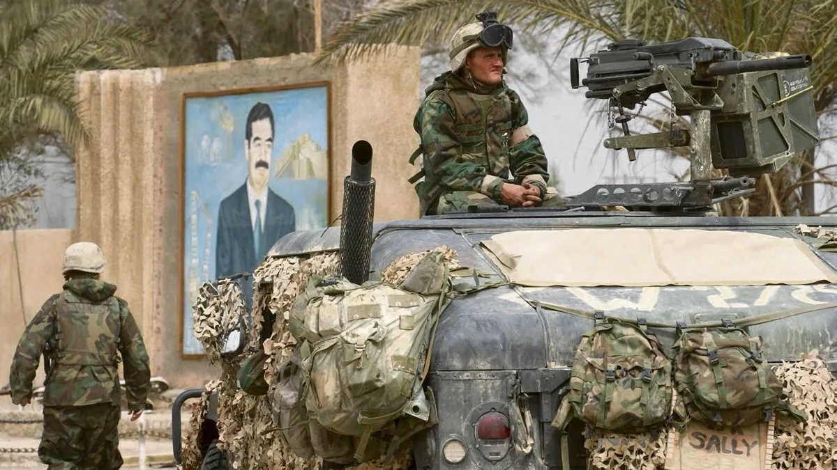 جنود أميركيون في الناصرية في 24 آذار (مارس) 2003 وتبدو في الخلفية صورة للرئيس العراقي الأسبق صدام حسين