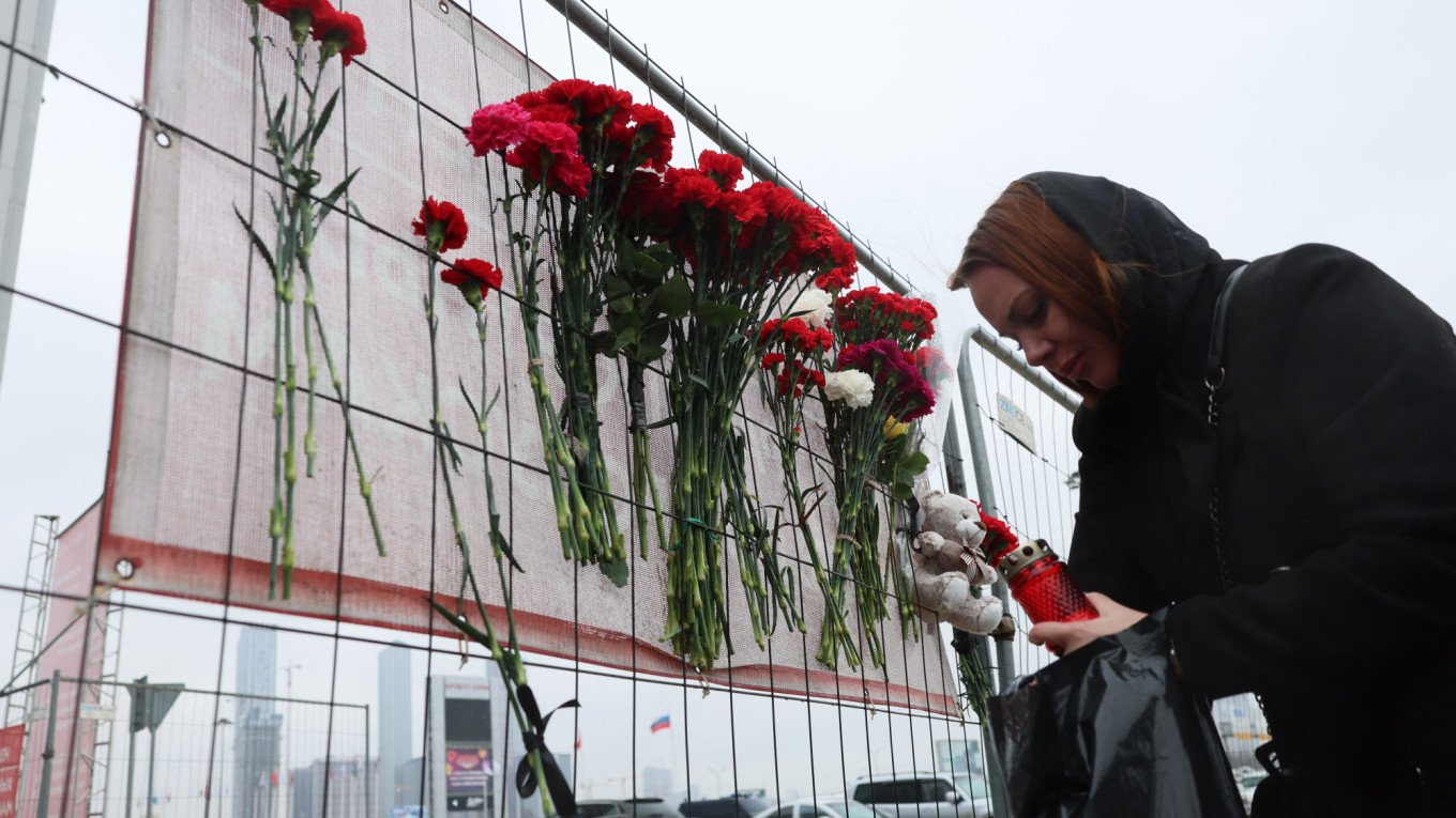 امرأة تضيء شموعاً تكريماً لضحايا التفجير الإرهابي في موسكو