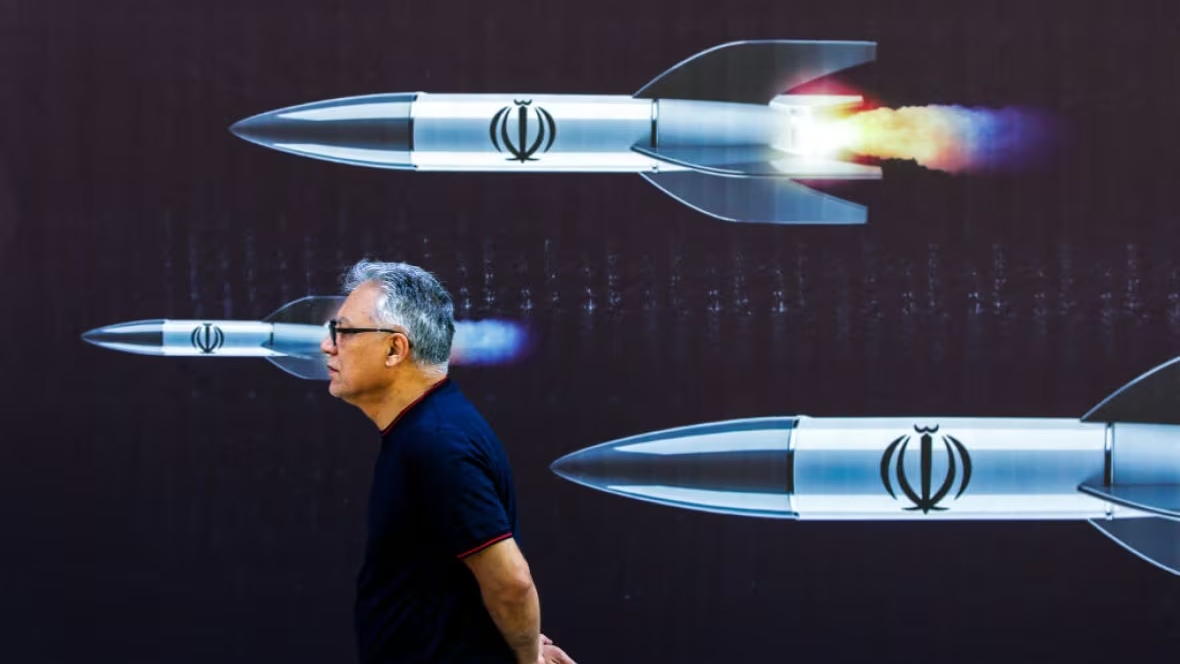 رجل يسير بمحاذاة جدارية في طهران تستعرض قدرات إيران الصاروخية