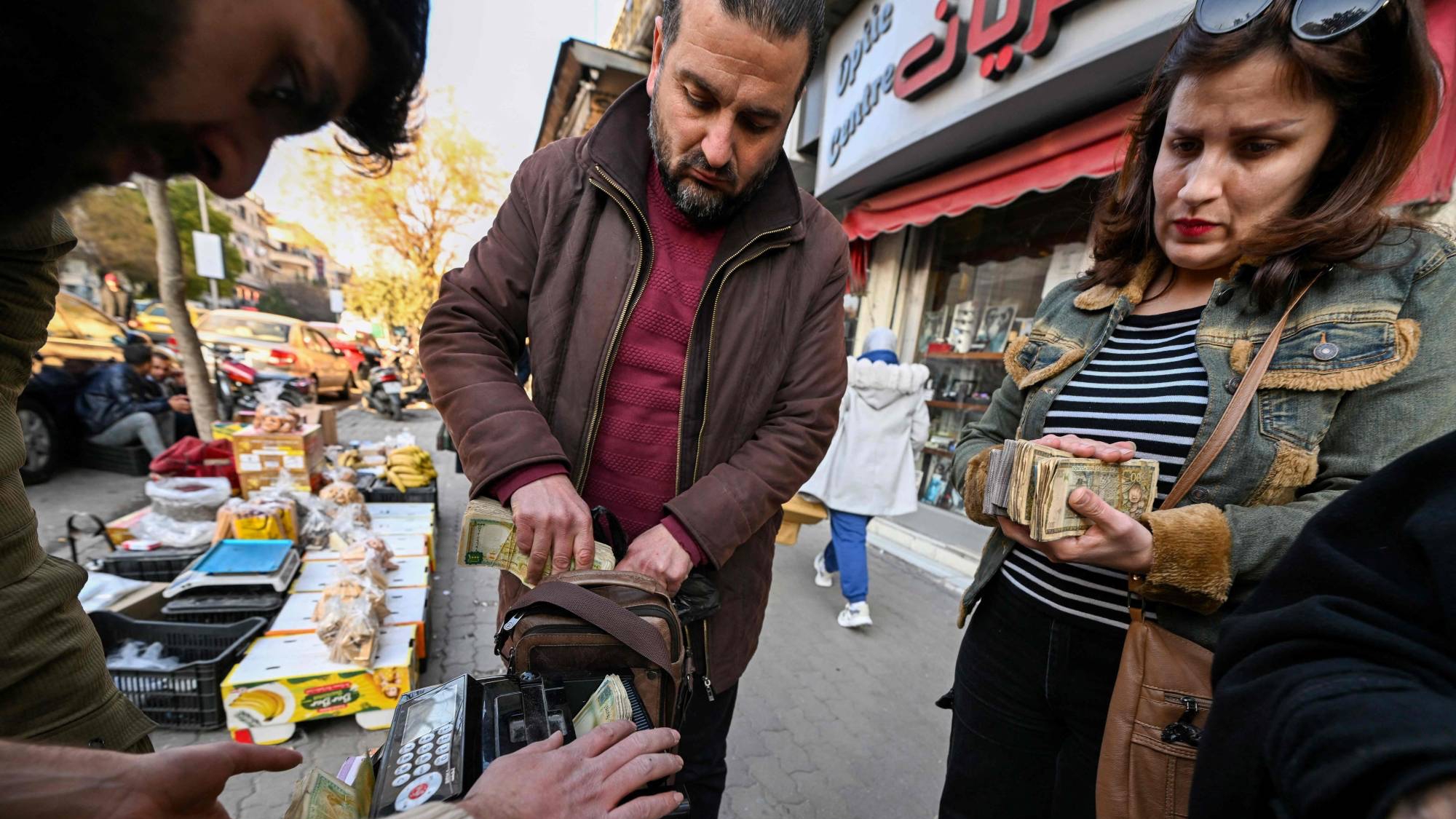 صراف يتعامل مع زبائن في أحد شوارع دمشق