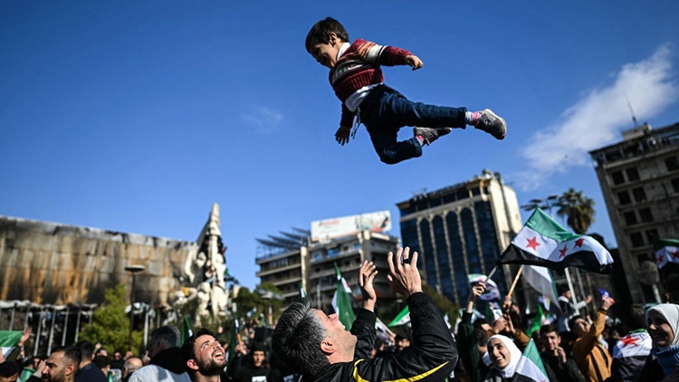 رجل يرمي طفلاً في الهواء فرحاً بسقوط نظام بشار الأسد في كانون الأول (ديسمبر) 2024