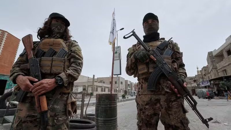 مقاتلان ينتميان إلى قوات الأمن الحكومية يقفان على حاجز يسد أحد مداخل جرمانا، اللصيقة بدمشق، يوم الأربعاء 30 نيسان (أبريل) 2025