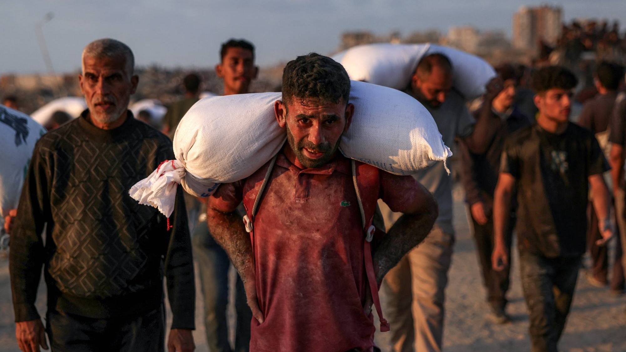 فلسطينيون يحملون أكياس دقيق غرب جباليا