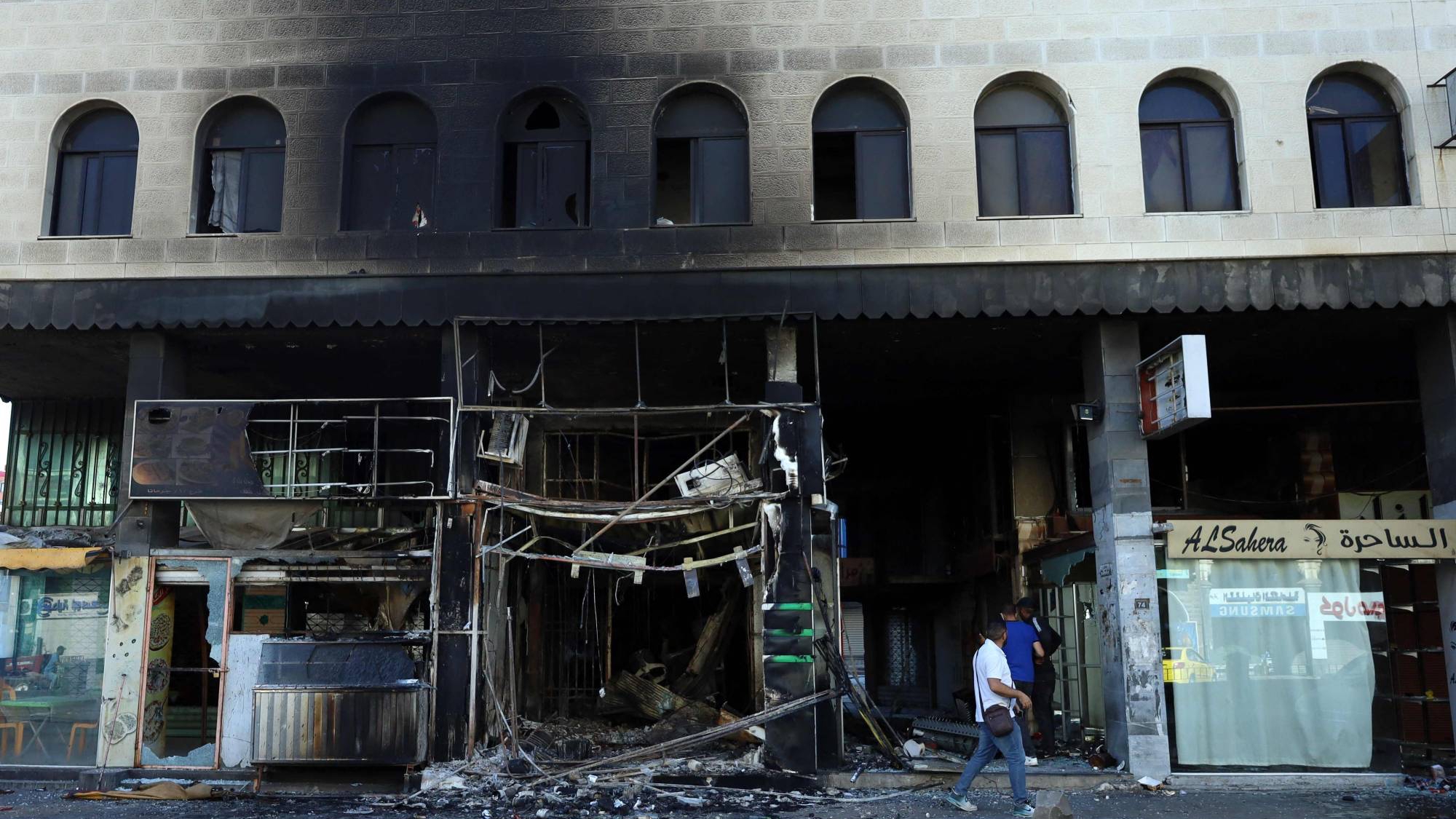 دروز من أبناء السويداء يتفقدون الأضرار التي لحقت بمبنى أضرمت فيه القوات السورية النار قبل انسحابها من السويداء يوم الخميس