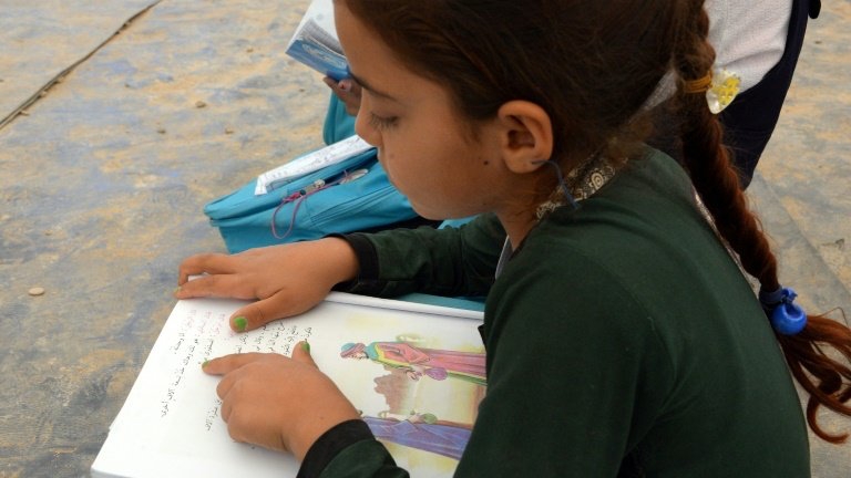 طفلة تقرأ في كتاب داخل إحدى مدارس العراق