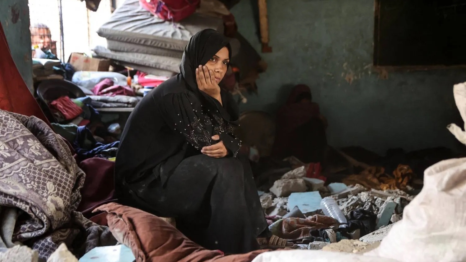 امرأة فلسطينية نازحة تجلس وسط الأنقاض في مدرسة تعرضت لغارة إسرائيلية بمدينة غزة