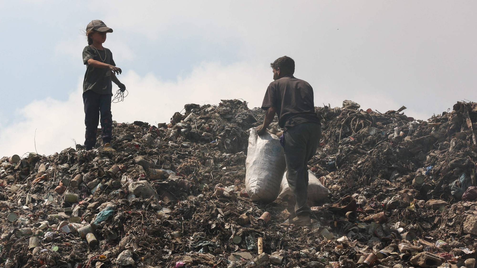فلسطينيان ينقِّبان وسط القمامة في مدينة غزة عن أي شيء قد ينفعهما