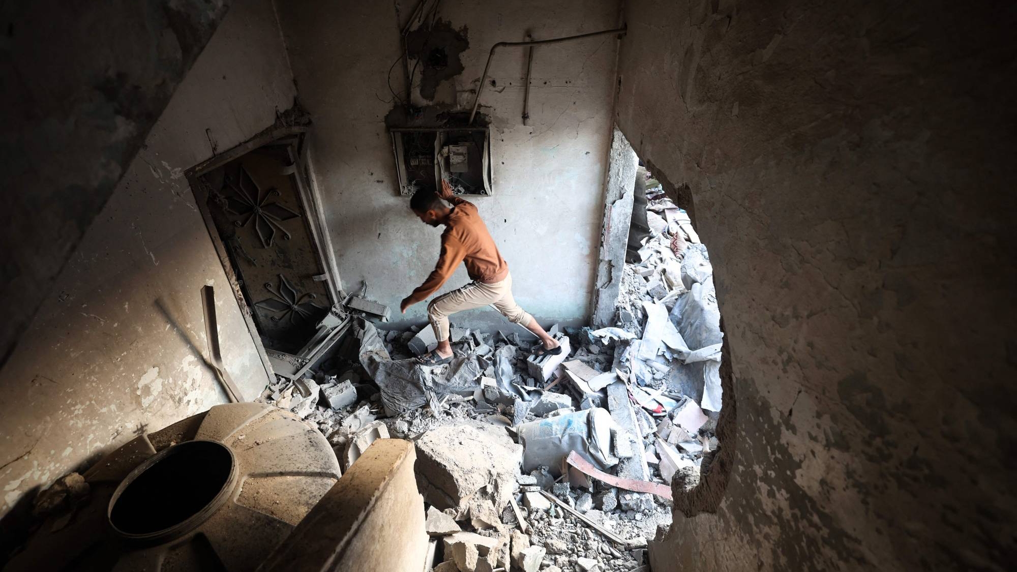 فلسطيني يسير وسط الركام داخل منزل أصابته ضربة إسرائيلية بمخيم النصيرات بوسط قطاع غزة الأحد