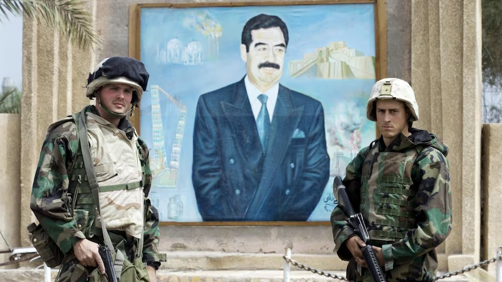 جنديان من المارينز يقفان لصورة تذكارية قرب نصب للرئيس العراقي الأسبق صدام حسين في الناصرية، في 24 آذار (مارس) 2003