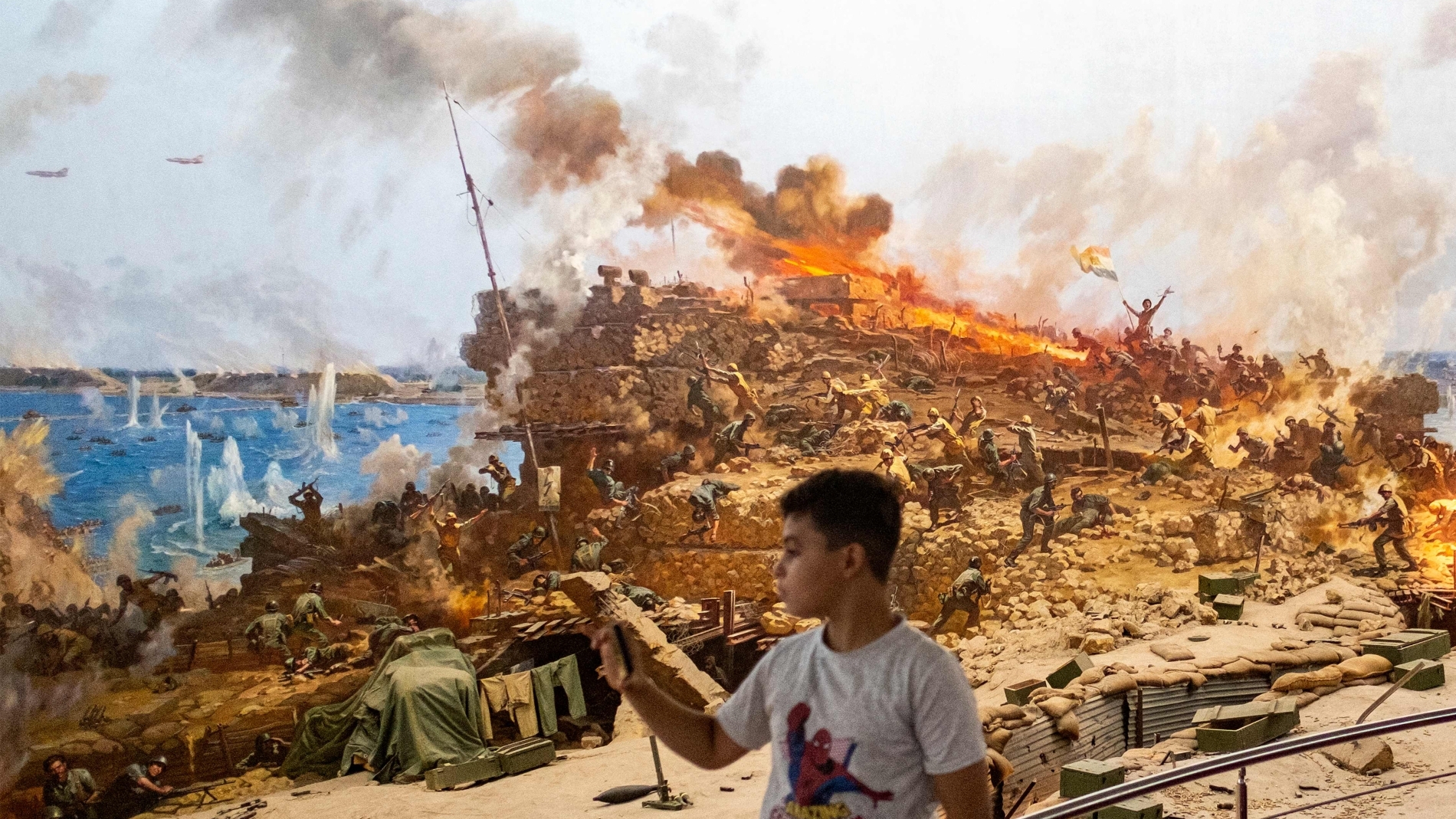 صبي يلتقط صورًا لمشهد حرب تمثيلي أثناء زيارته متحف 