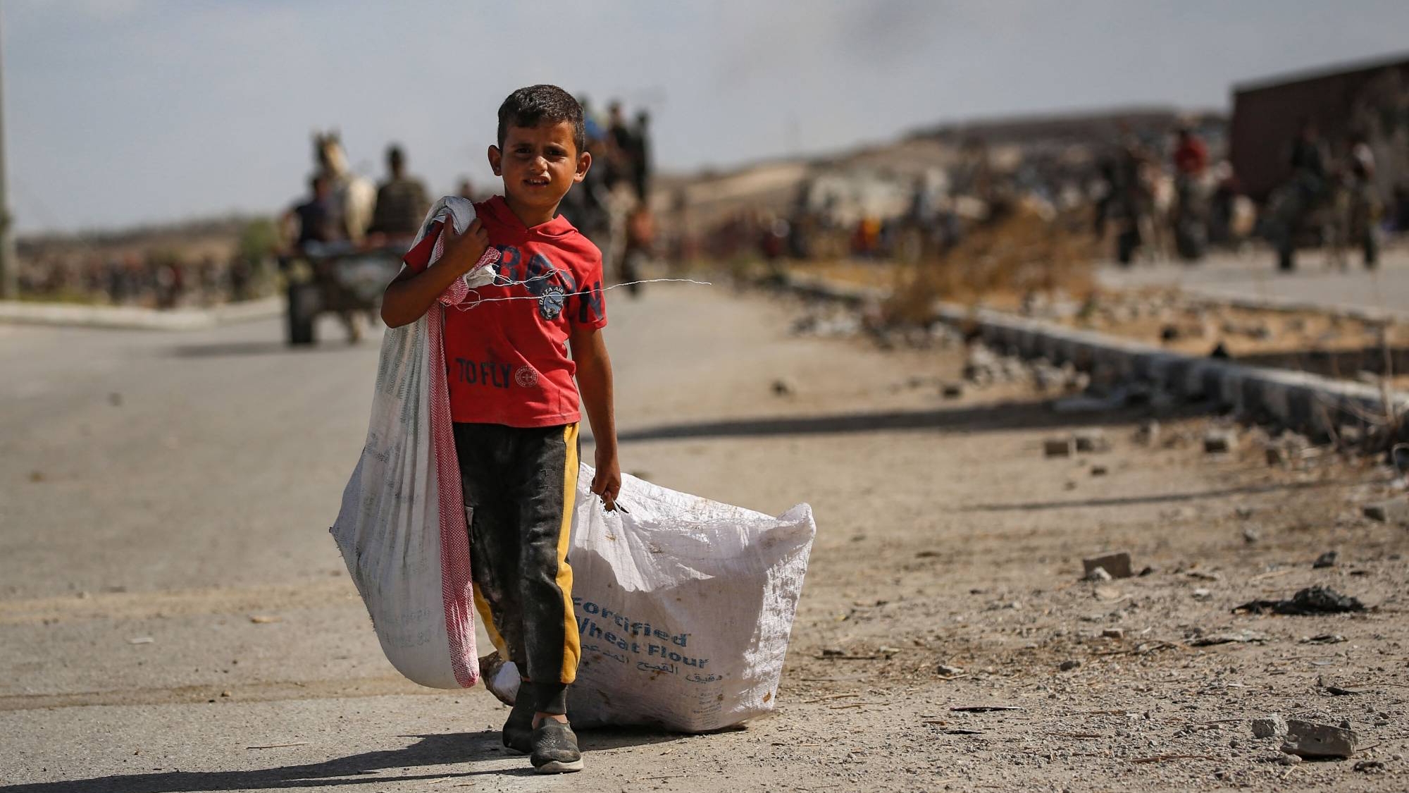 طفل عائد بطعام ودواء من مركز مساعدات في غزة
