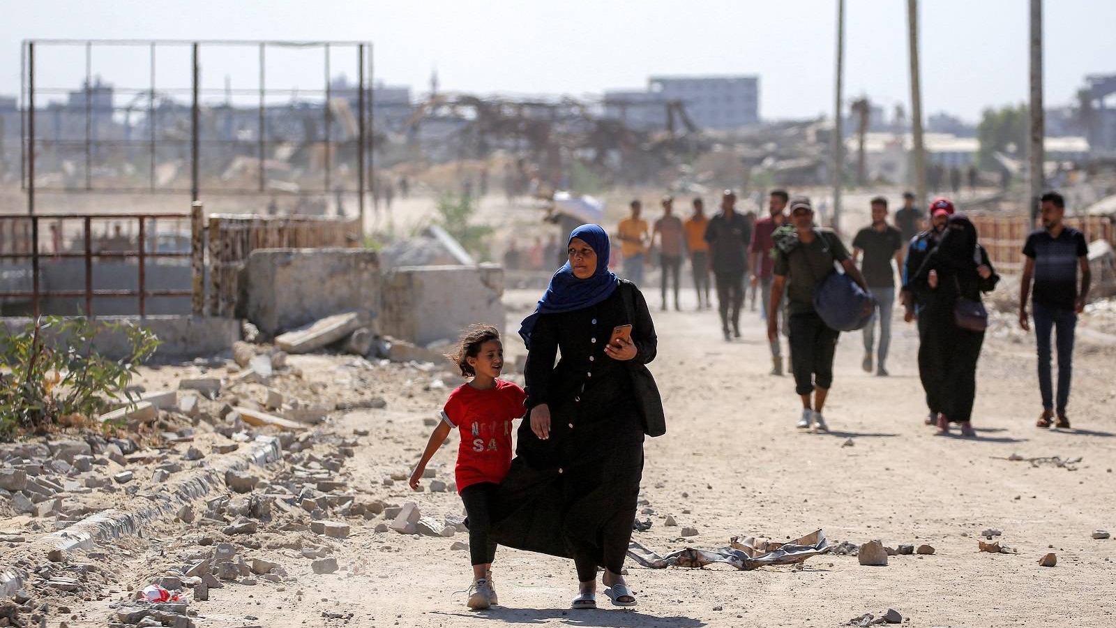 امرأة تسير مع فتاة في طريقها إلى مدينة غزة عبر ما يسمى ممر نتساريم من النصيرات وسط قطاع غزة