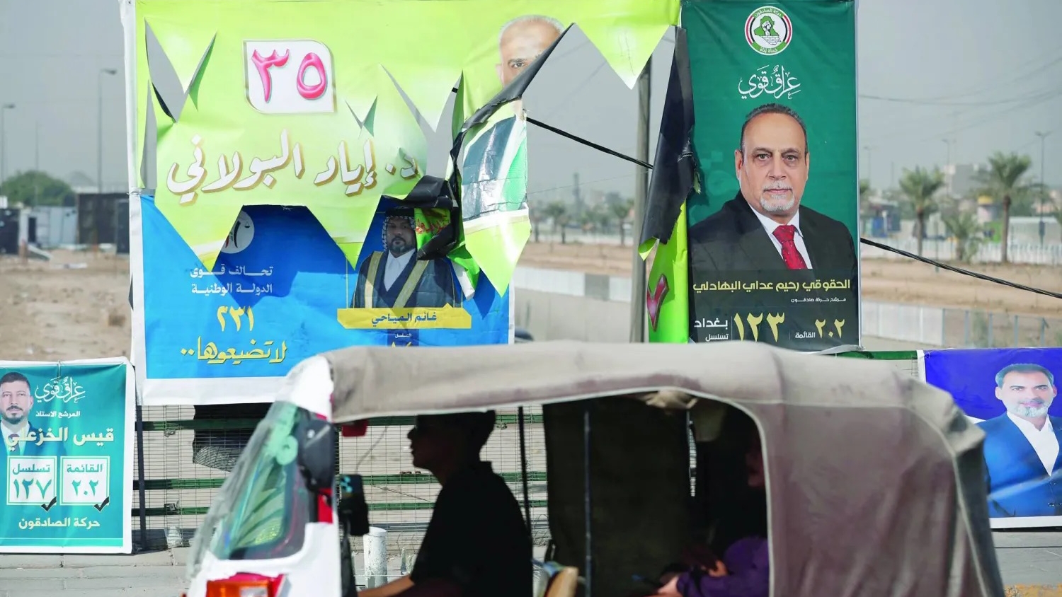 مركبة تمر أمام ملصقات انتخابية بمدينة الصدر شرق بغداد استعداداً للانتخابات البرلمانية