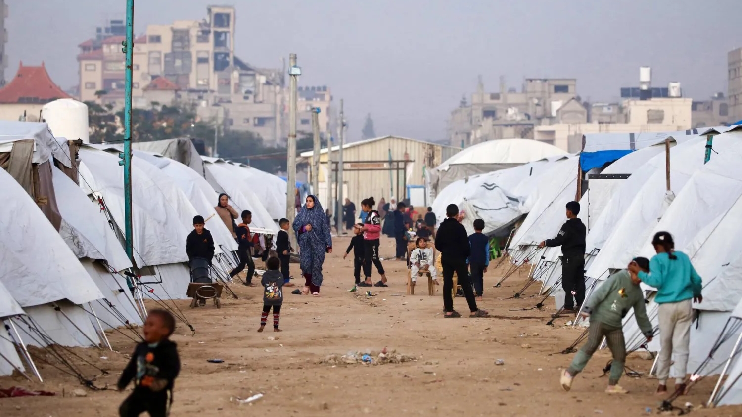 فلسطينيون يسيرون وسط الملاجئ في مخيم النصيرات للنازحين الفلسطينيين بغزة