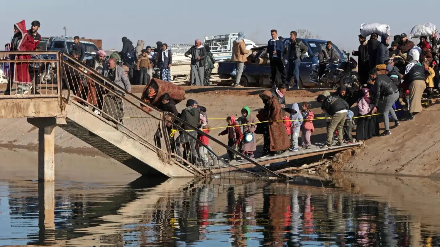 سكان يعبرون جسراً متضرراً لدى فرارهم من منطقة تسيطر عليها قوات «قسد» شرق مدينة حلب
