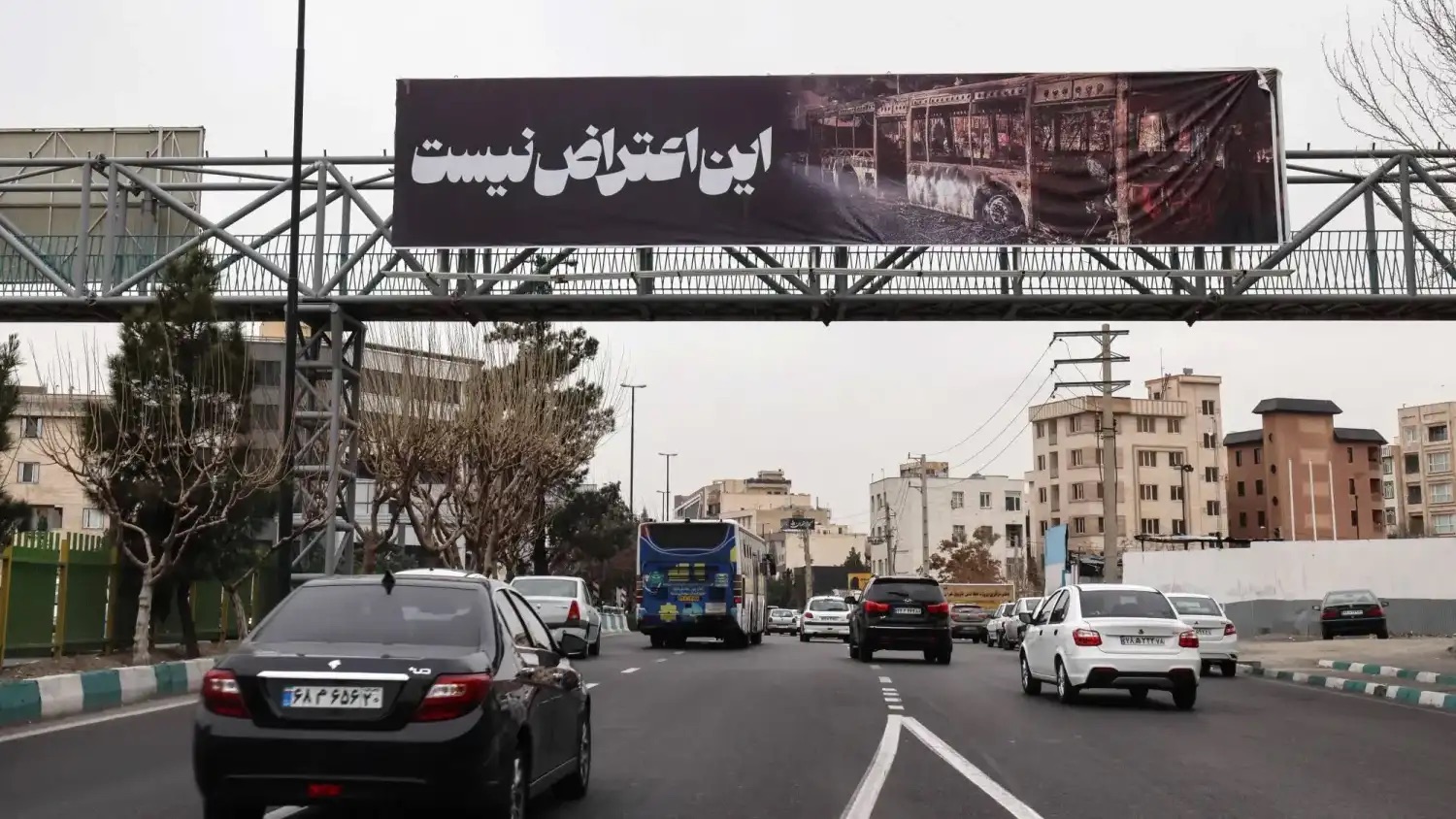 سيارات تسير في طهران تحت لافتة كتب عليها «هذا ليس احتجاجاً» الخميس