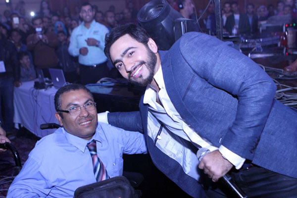 تامر حسني يلتقط الصورة مع الضيف من ذوي الإحتياجات الخاصة