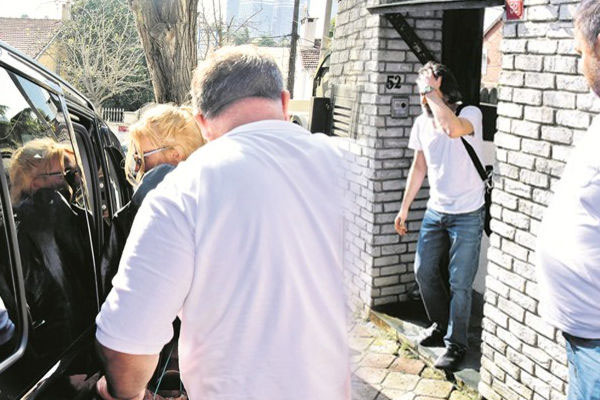 مريم أوزيرلي تُهرِّب ابنتها من الصحافيين قرب السيارة ويبدو أوزان غوفان على باب منزله