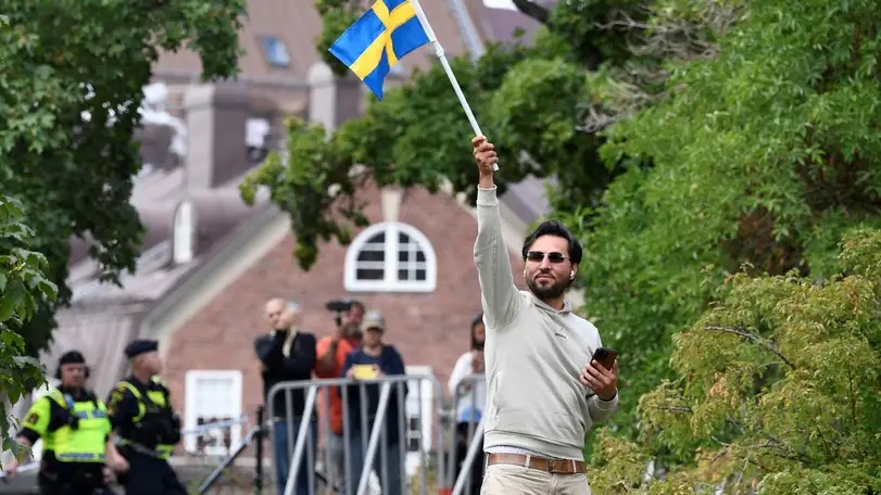 اللاجئ العراقي سلوان موميكا رافعا العلم السويدي في صيف 2023