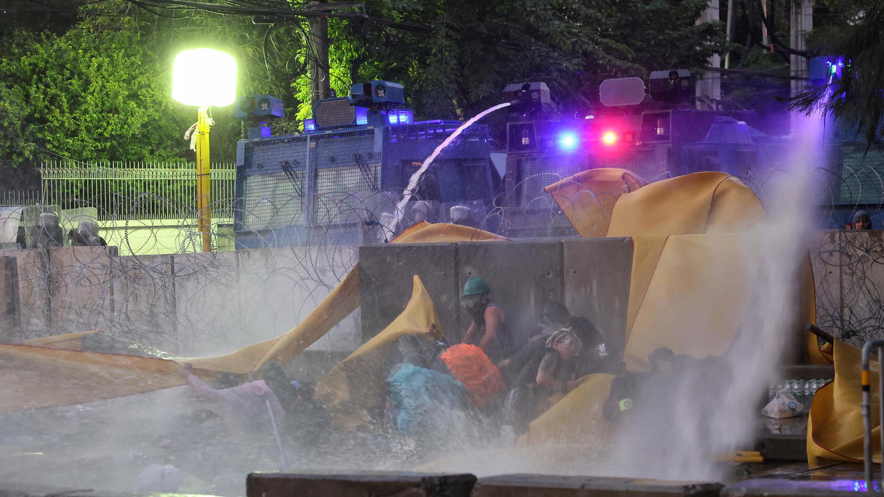 متظاهرون مطالبون بتعزيز الديموقراطية يحتمون من خراطيم المياه الممزوجة بمادة كيميائية التي تطلقها الشرطة لفض تظاهرة في بانكوك في 17 تشرين الثاني/نوفمبر 2020
