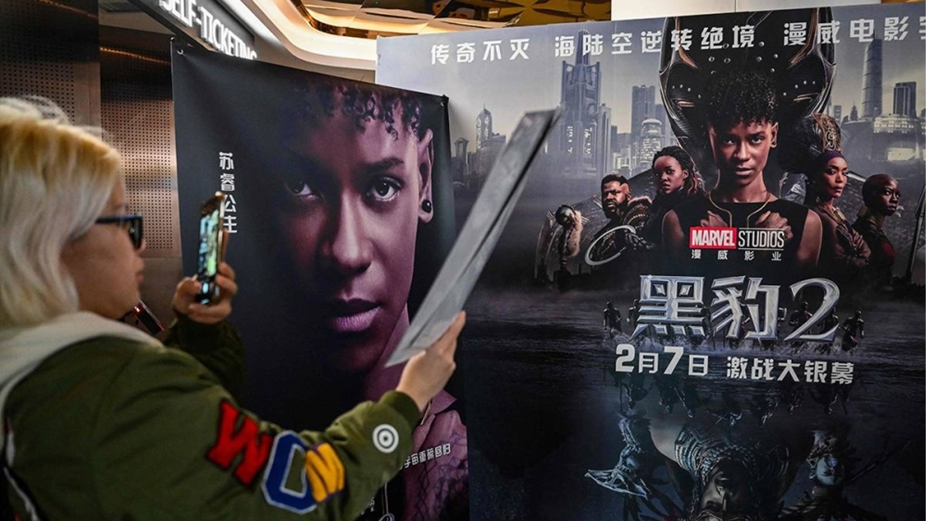 شابة تلتقط صورة لملصق فيلم «بلاك بانثر: واكاندا فوريفر» في إحدى دور السينما في شنغهاي