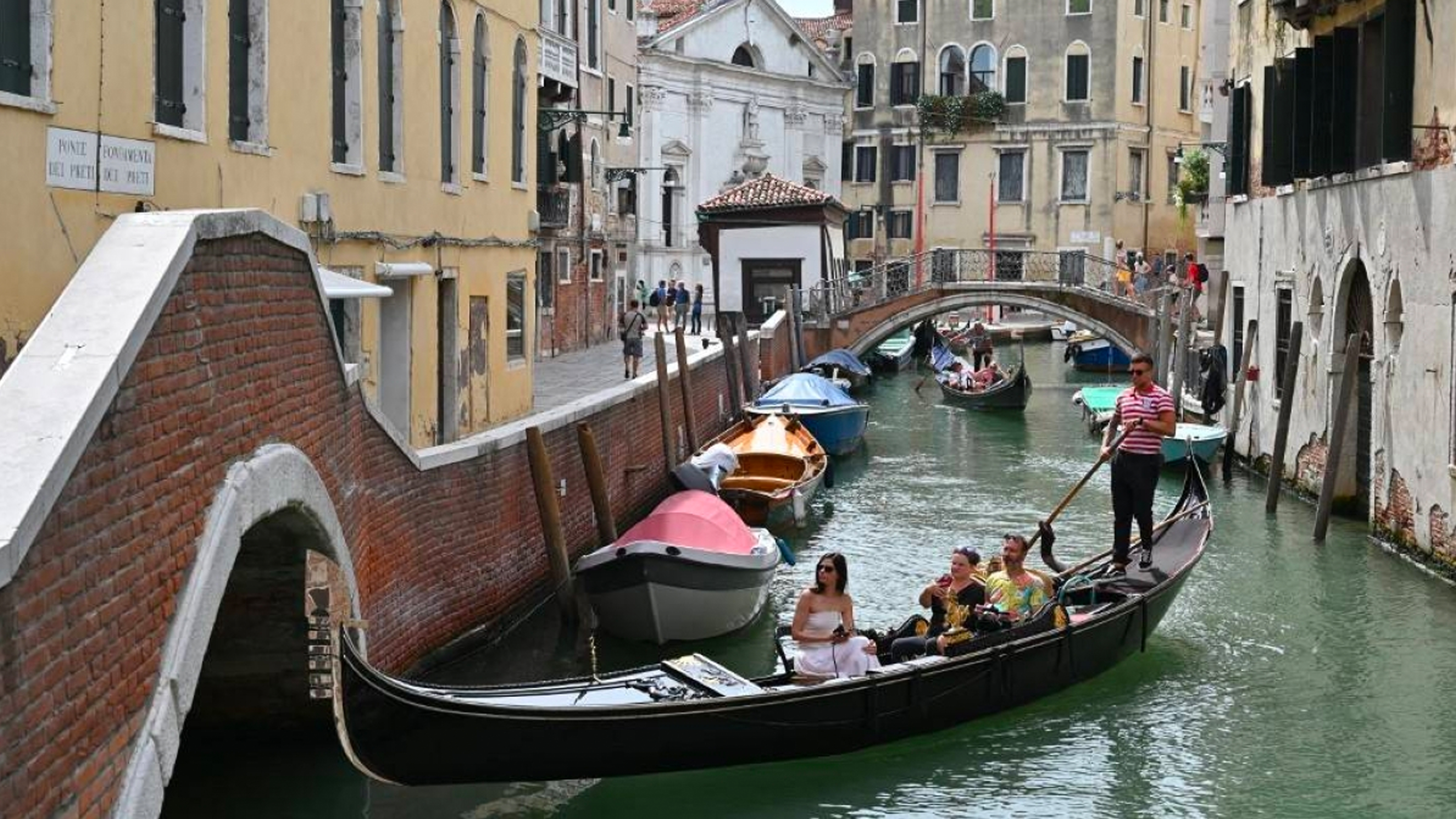 سياح في جولة بالجندول عبر قناة في مدينة البندقية ، شمال إيطاليا ، يوم الاثنين ، 31 يوليو ، 2023. AFP PHOTO