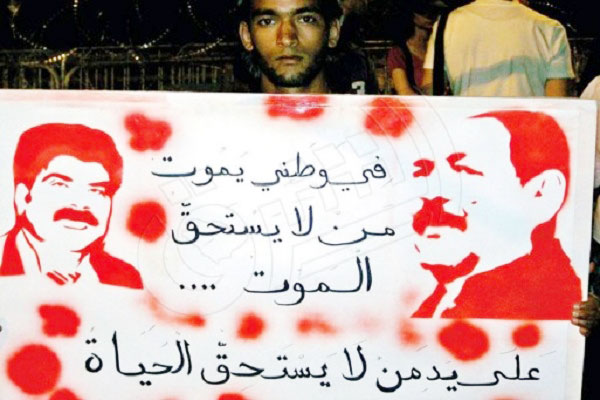 متظاهر تونسي يرفع لافتة تحمل صورتي شكري بلعيد ومحمد البراهمي