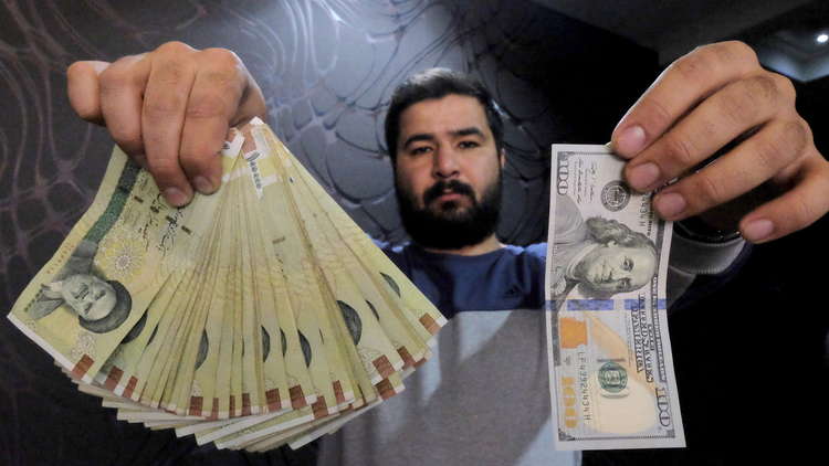 صراف ايراني بين دولارات وريالات ايرانية