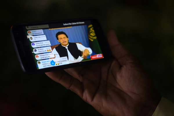 باكستاني يتابع عبر هاتفه المحمول أول خطاب لرئيس الوزراء الجديد عمران خان في كراتشي بتاريخ 19 أغسطس 2018
