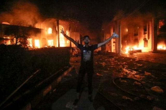 عراقي يرفع شارة النصر أمام القنصلية الإيرانية بعد إحراقها 