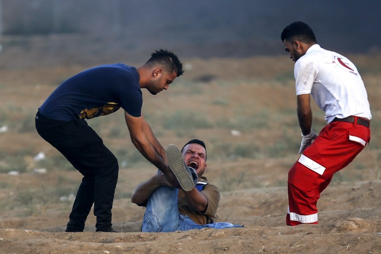 شاب فلسطيني ومسعف يحاولان اسعاف شاب اصيب في تظاهرات جمعة الغضب قرب غزة