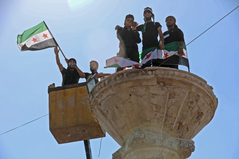 نشطاء يلوحون بأعلام الثورة السورية في إدلب خلال تظاهرات مناوئة للنظام