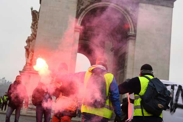متظاهر يحمل شعلة مضيئة أمام قوس النصر على جادة الشانزيليزيه في باريس السبت 1 ديسمبر 2018