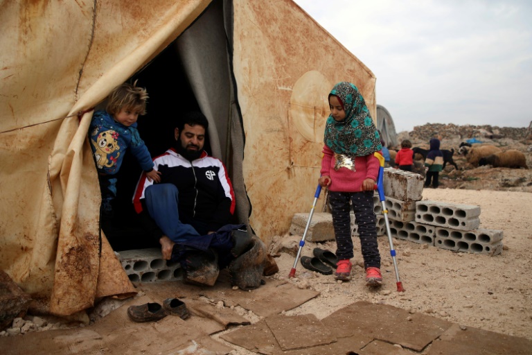 مايا مرعي الى جانب والدها المعوق امام خيمة عائلتها في احد المخيمات في شمال غرب سوريا في التاسع من ديسمبر 2018