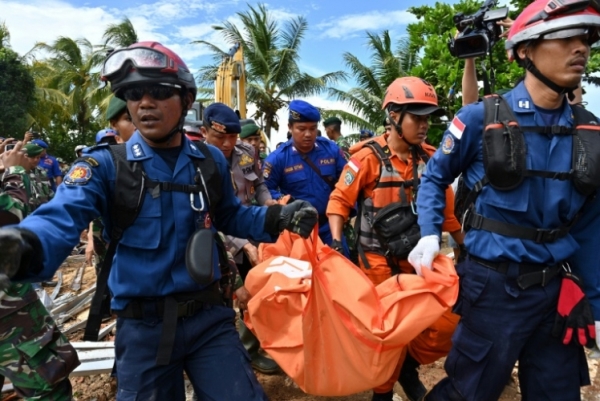 أعضاء من فرق الإنقاذ الإندونيسية يحملون جثةً عثر عليها في كاريتا بعد يومين من كارثة تسونامي