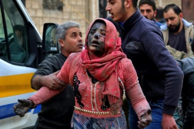 رجل سوري يساعد امرأة غطاتها الغبار الناجمة عن القصف الذي استهدف خان شيخون في إدلب بتاريخ 15 شباط/فبراير 2019